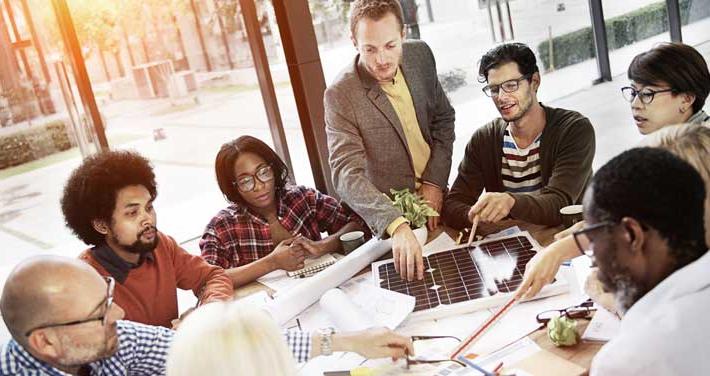 A business team around a table looking at a solar panel